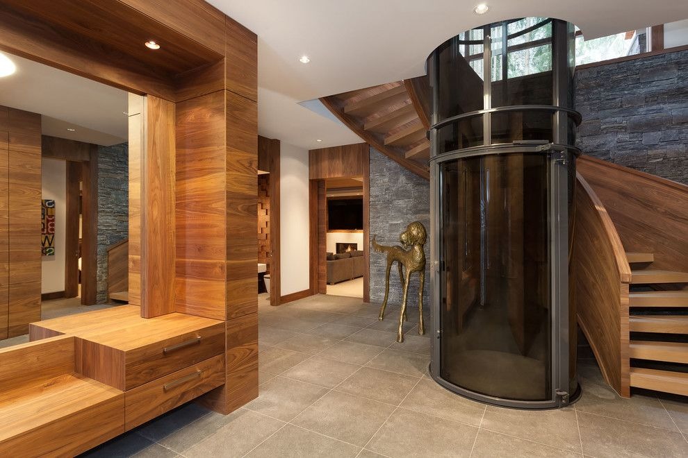 Modern vacuum home elevator installed beside a curved staircase for improved accessibility.