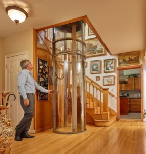 Glass home elevator installed beside a staircase, showing a space-saving alternative to a stairlift for long-term home accessibility.