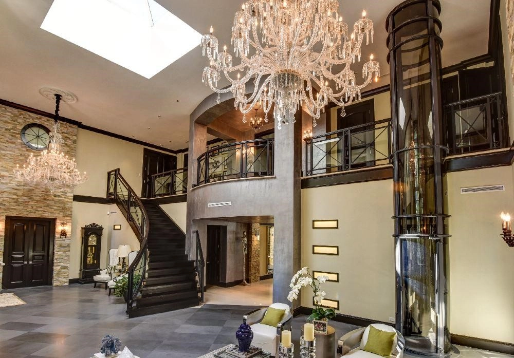 Luxury residential vacuum elevator installed beside a staircase in a grand home interior