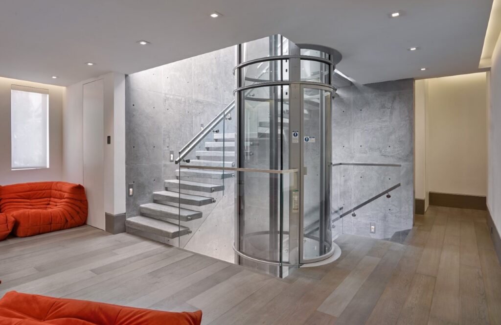 Glass pneumatic vacuum elevator in a modern residential interior with staircase