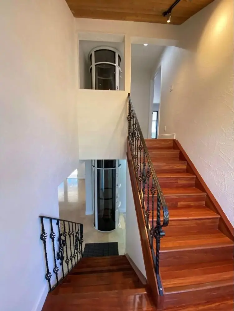Compact residential vacuum elevator providing multi-floor accessibility in an existing home with limited space.